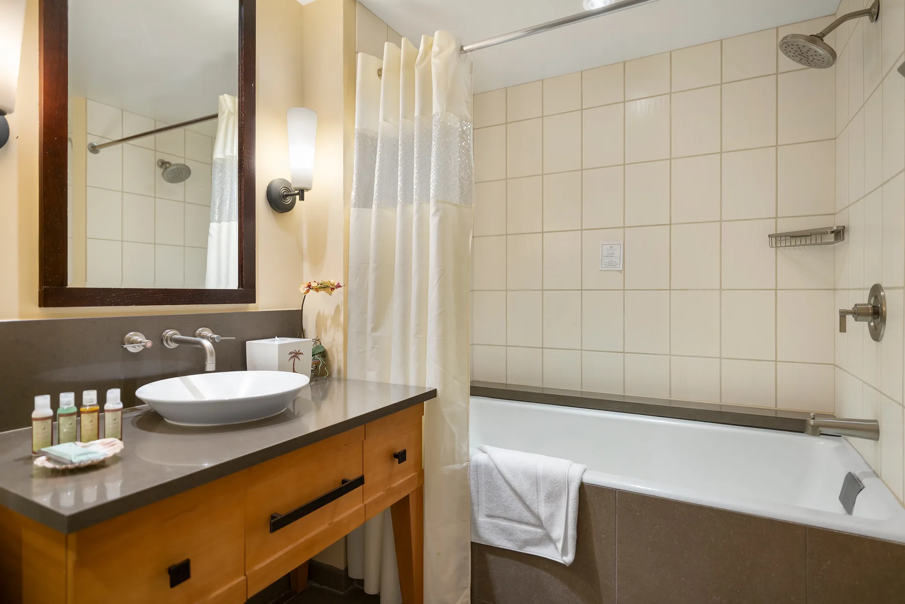 Un baño con azulejos, bañera y tocador con lavabo.