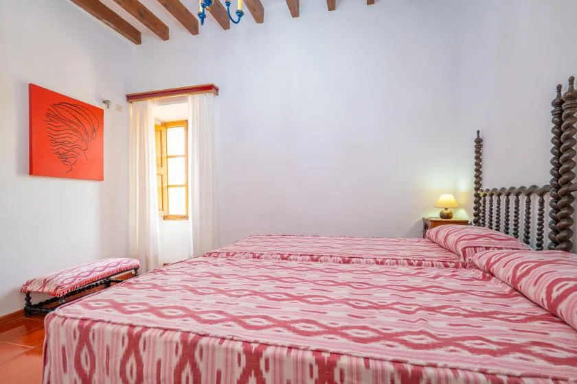 A bedroom with a large bed covered in pink patterned bedding.