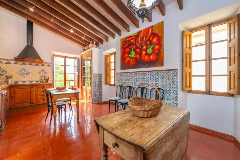 A kitchen and dining area with wooden tables, patterned tile, and colorful wall art.