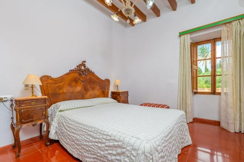A bedroom with a large bed, wooden headboard, and a window with curtains.