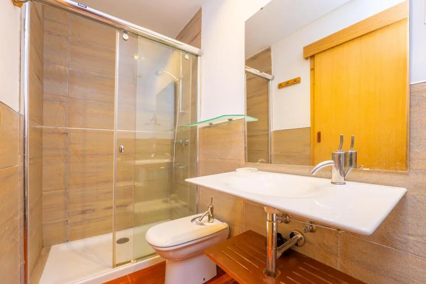 A bathroom with a glass shower, sink, and toilet.