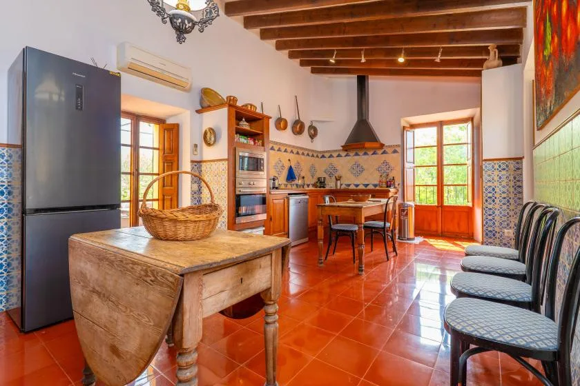 A dining room with a wooden table and chairs beneath exposed ceiling beams.