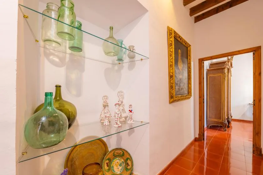 A hallway with glass shelves displaying decorative bottles and ceramics.