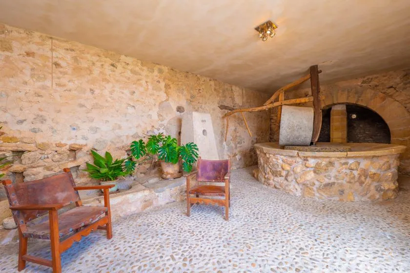 A rustic stone room with a round masonry structure and wooden seating.