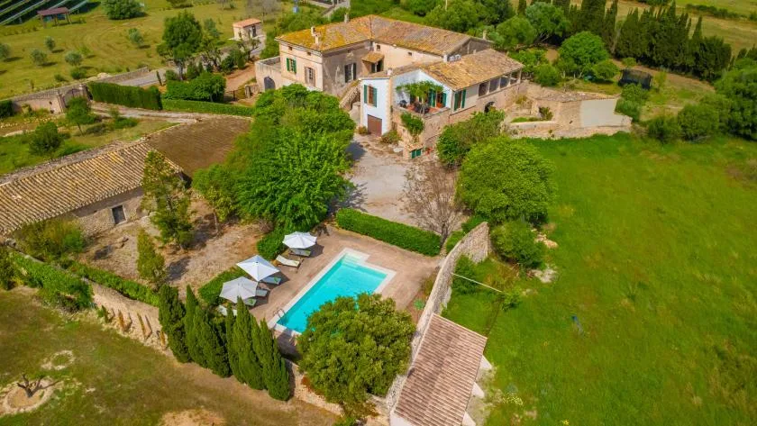 A countryside property with a swimming pool beside a large house.