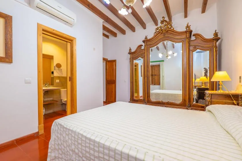 A bedroom with a large mirrored wardrobe and a bed.