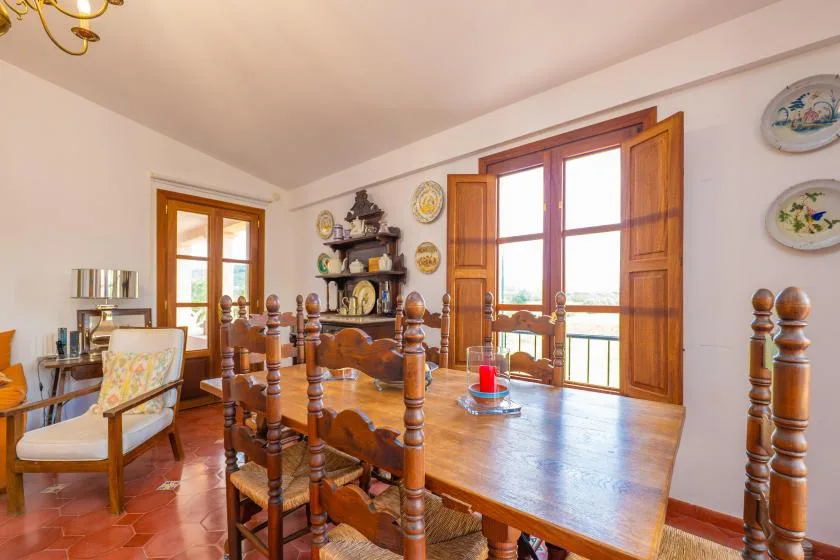A dining room with a long wooden table and large windows.