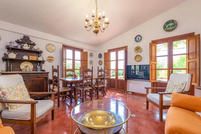 A living and dining room with wooden seating and tall windows.