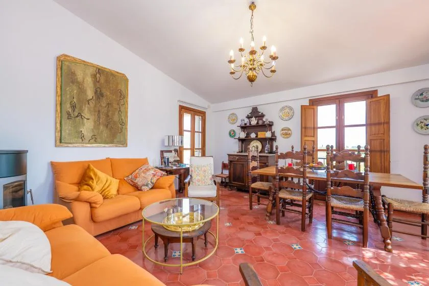 A living and dining room with orange seating, a wooden table, and a chandelier.