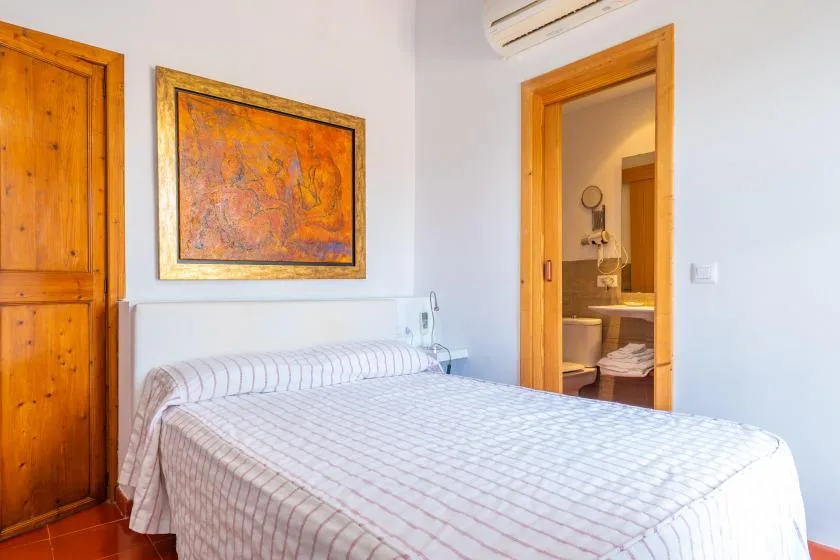 A bedroom with a neatly made bed and a doorway to the bathroom.