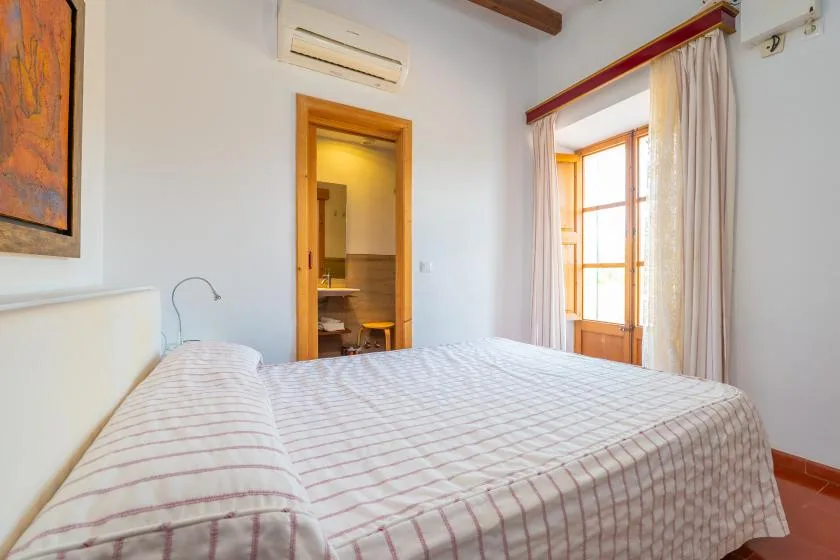 A bright bedroom with a bed and a curtained window.