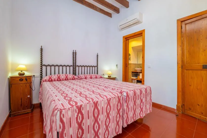 A bedroom with a large bed covered in a patterned pink bedspread.