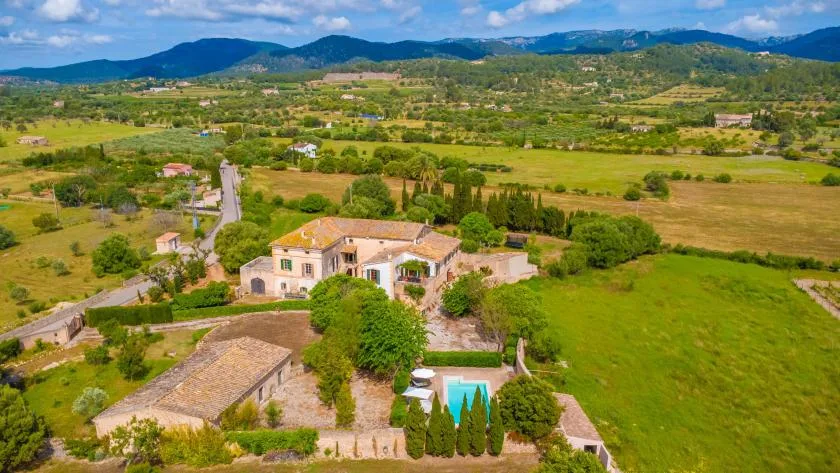 Aerial view of a rural estate with stone buildings, gardens, and green fields.