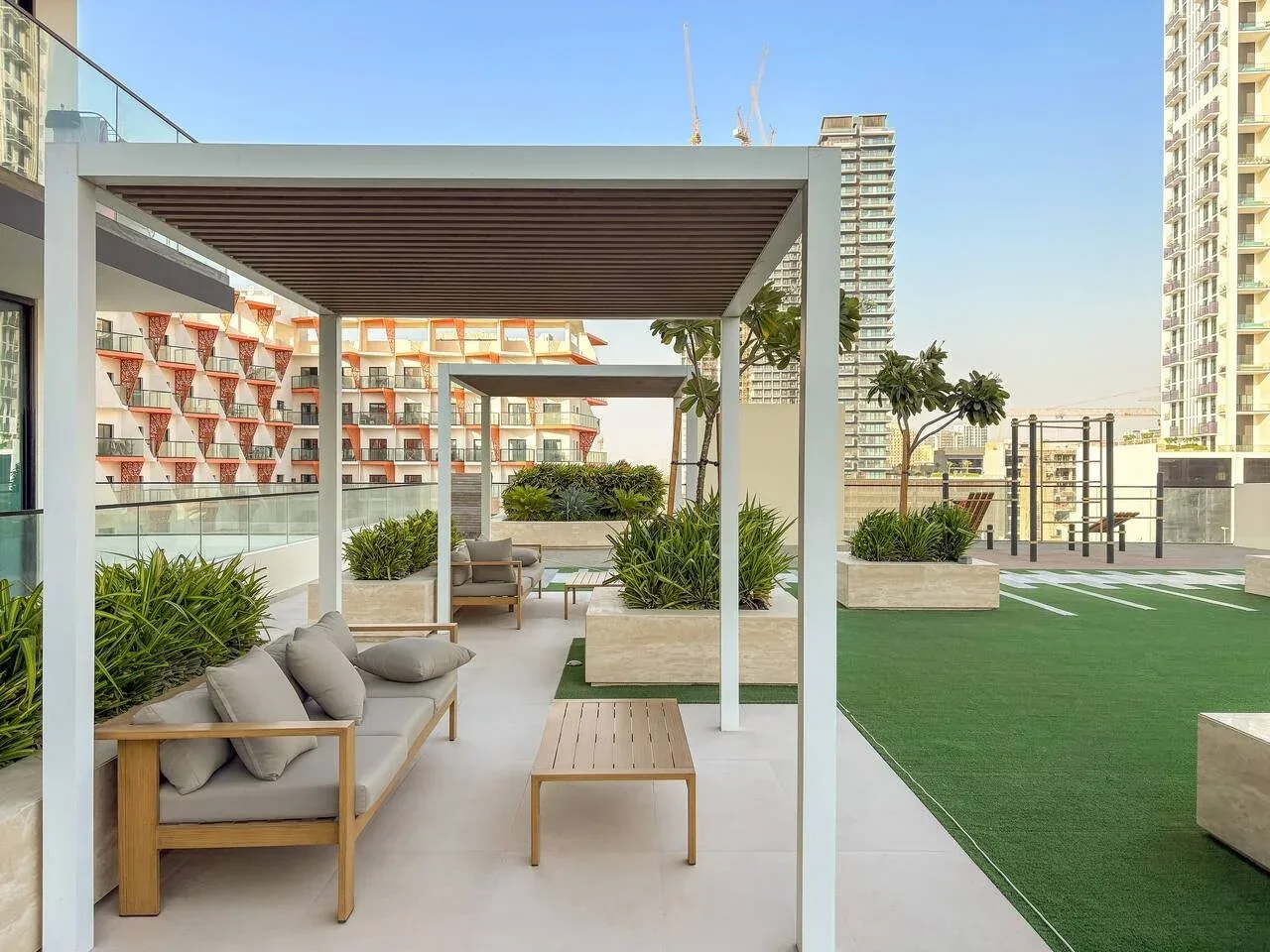 Una terraza en la azotea con asientos al aire libre, jardineras y una zona de césped verde.