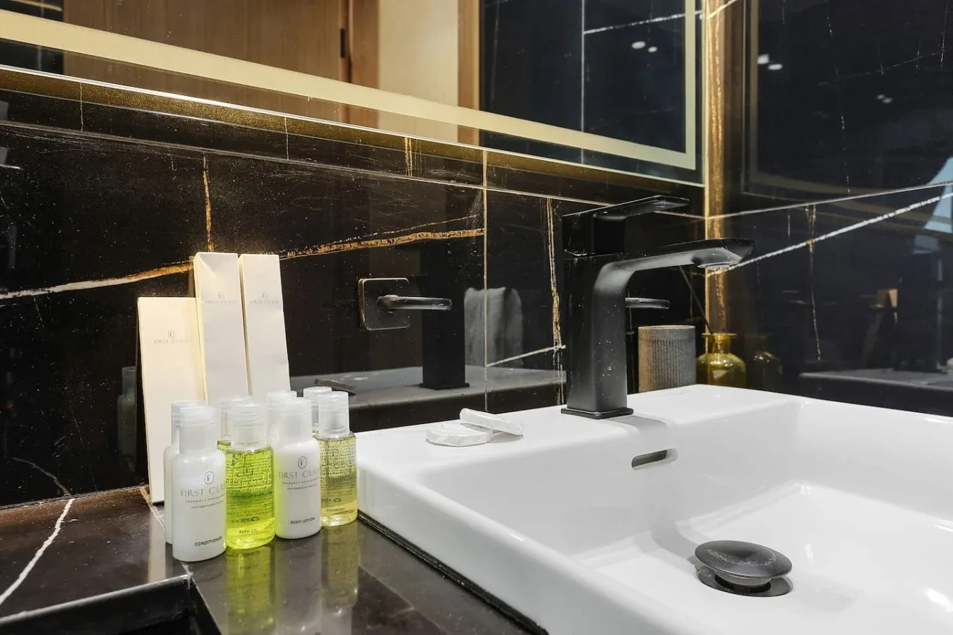 Un lavabo de baño con un lavamanos blanco, una encimera oscura y artículos de aseo.