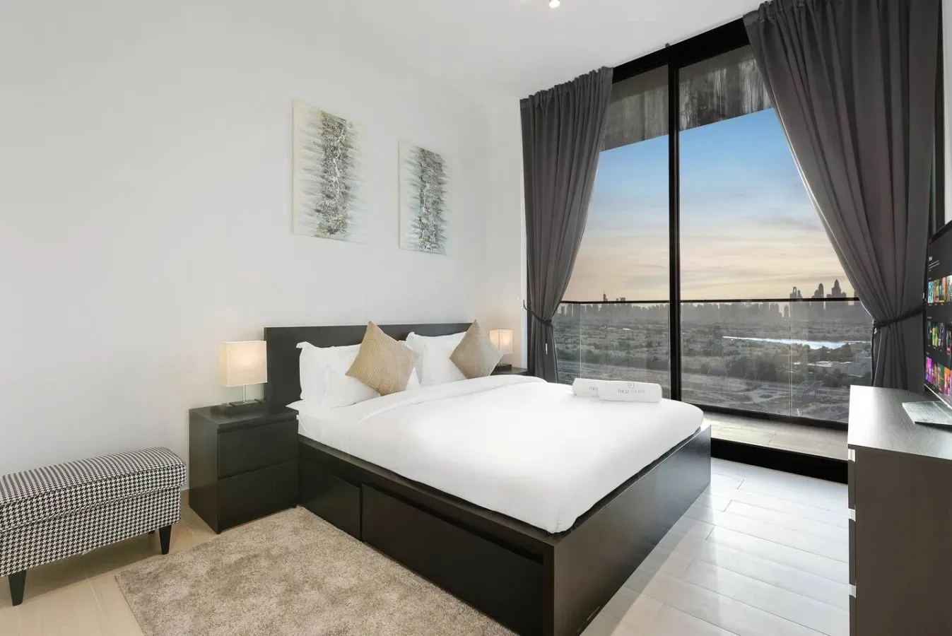 Un dormitorio luminoso con una cama bien tendida junto a una ventana grande.