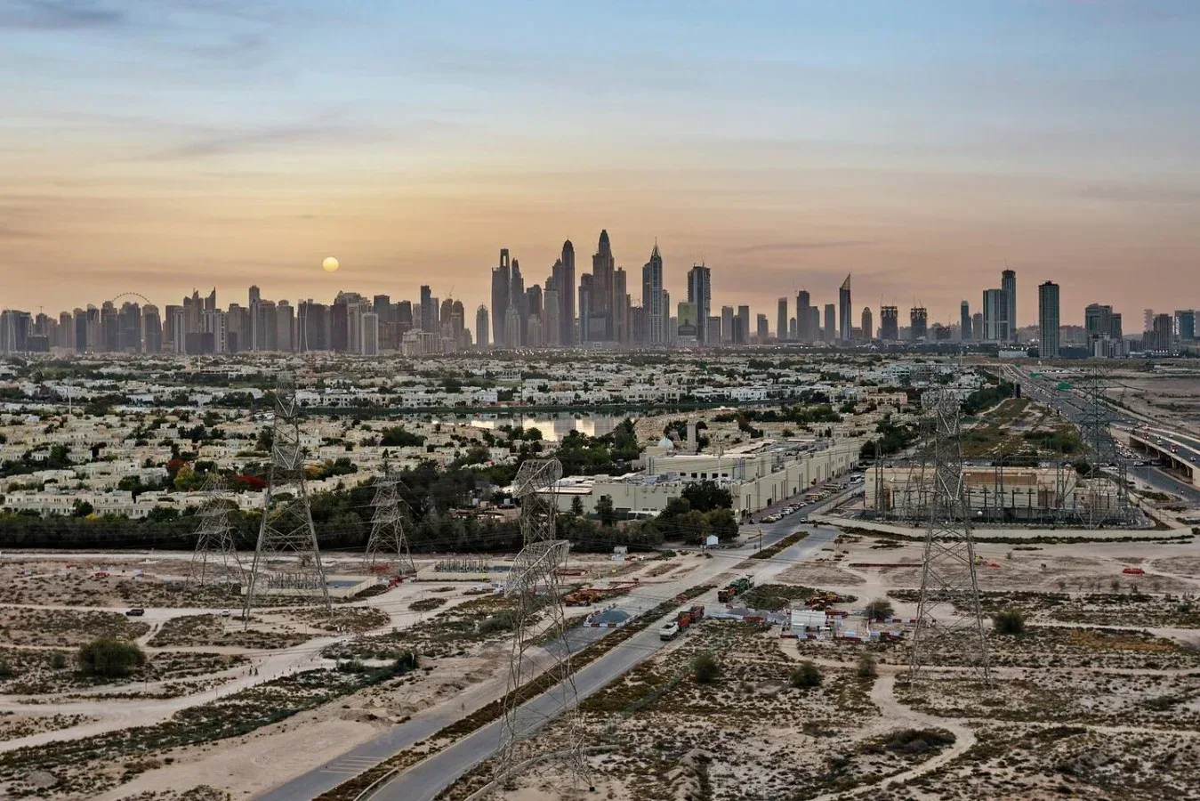Un horizonte urbano se alza detrás de una amplia extensión de edificios bajos y terreno abierto.
