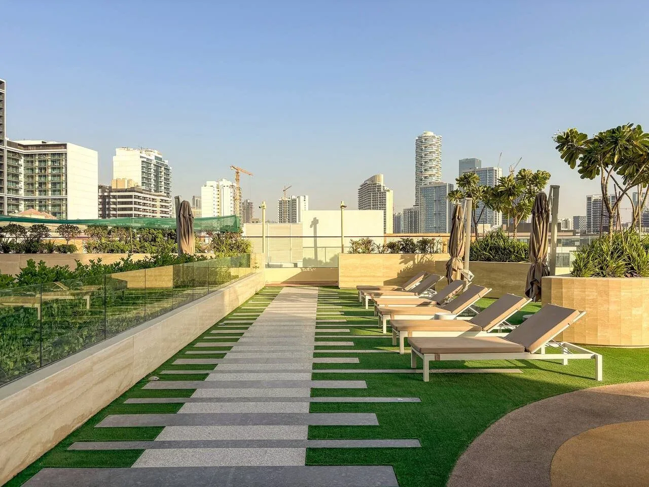 Una terraza en la azotea tiene asientos junto a un camino a rayas, con edificios de la ciudad al fondo.
