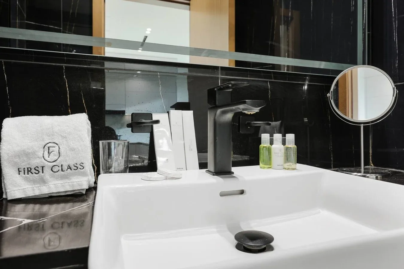 Un lavabo de baño con grifo oscuro, artículos de aseo y una toalla sobre la encimera negra.