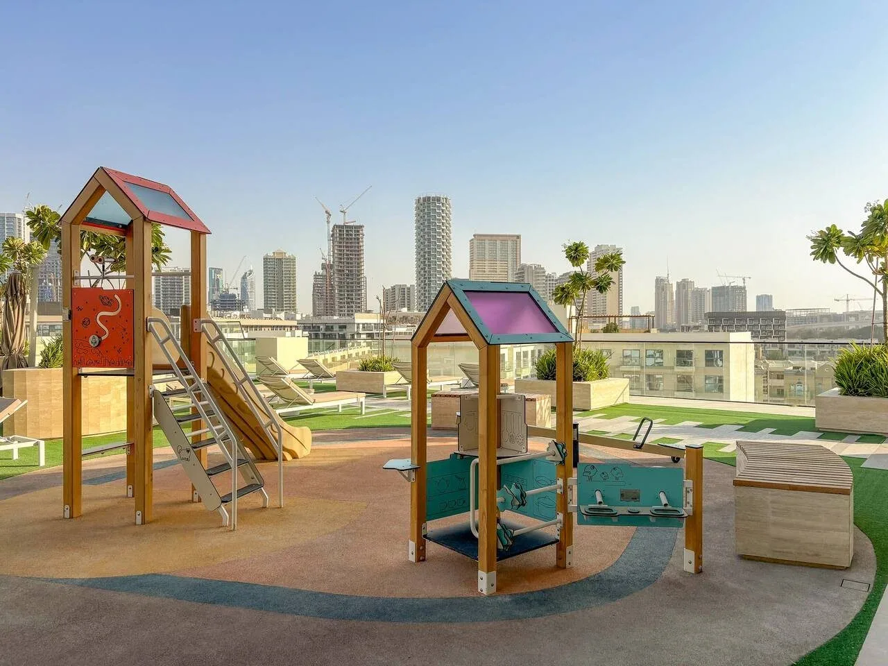Un parque infantil en la azotea con juegos de colores da a un horizonte urbano.
