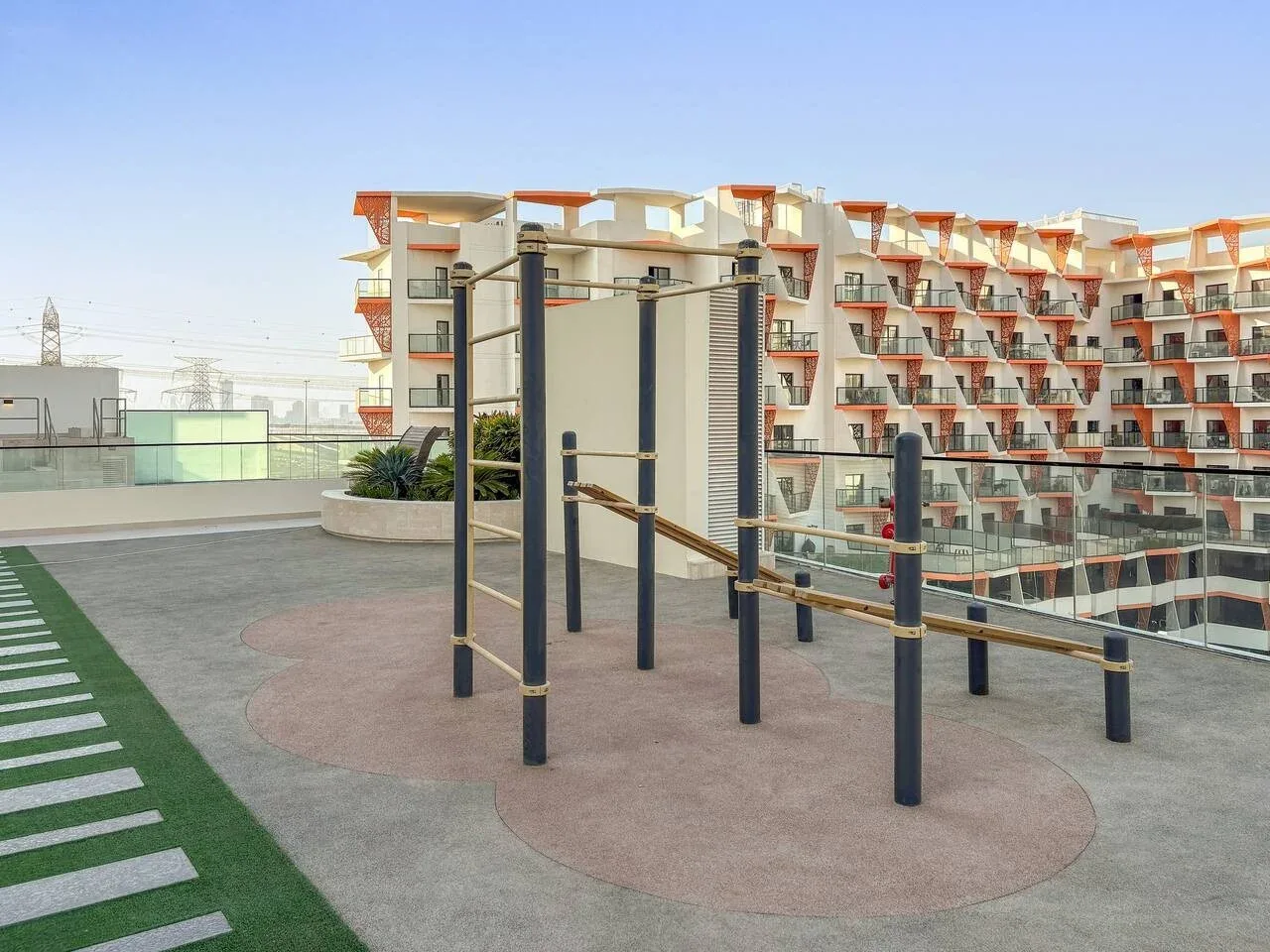 Un área de ejercicio al aire libre con barras paralelas está junto a un edificio moderno.