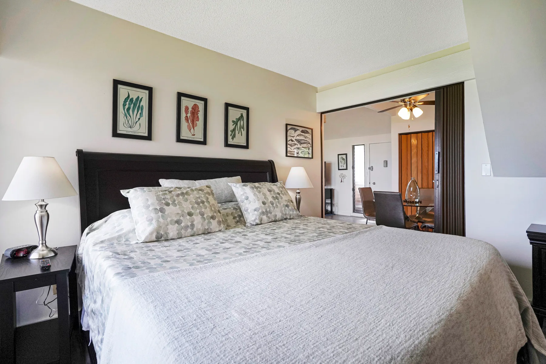 A bedroom with a large bed, bedside tables, and framed artwork on the wall.