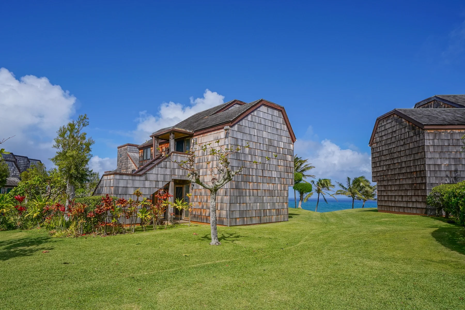 A shingled building stands on a green lawn beneath a clear blue sky.