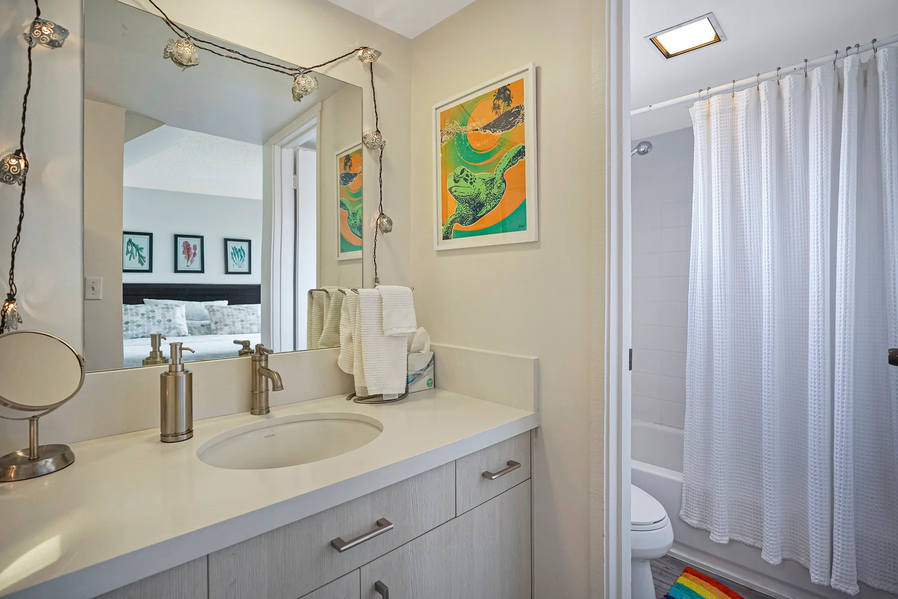 A bathroom vanity with a sink and mirror beside a curtained shower.
