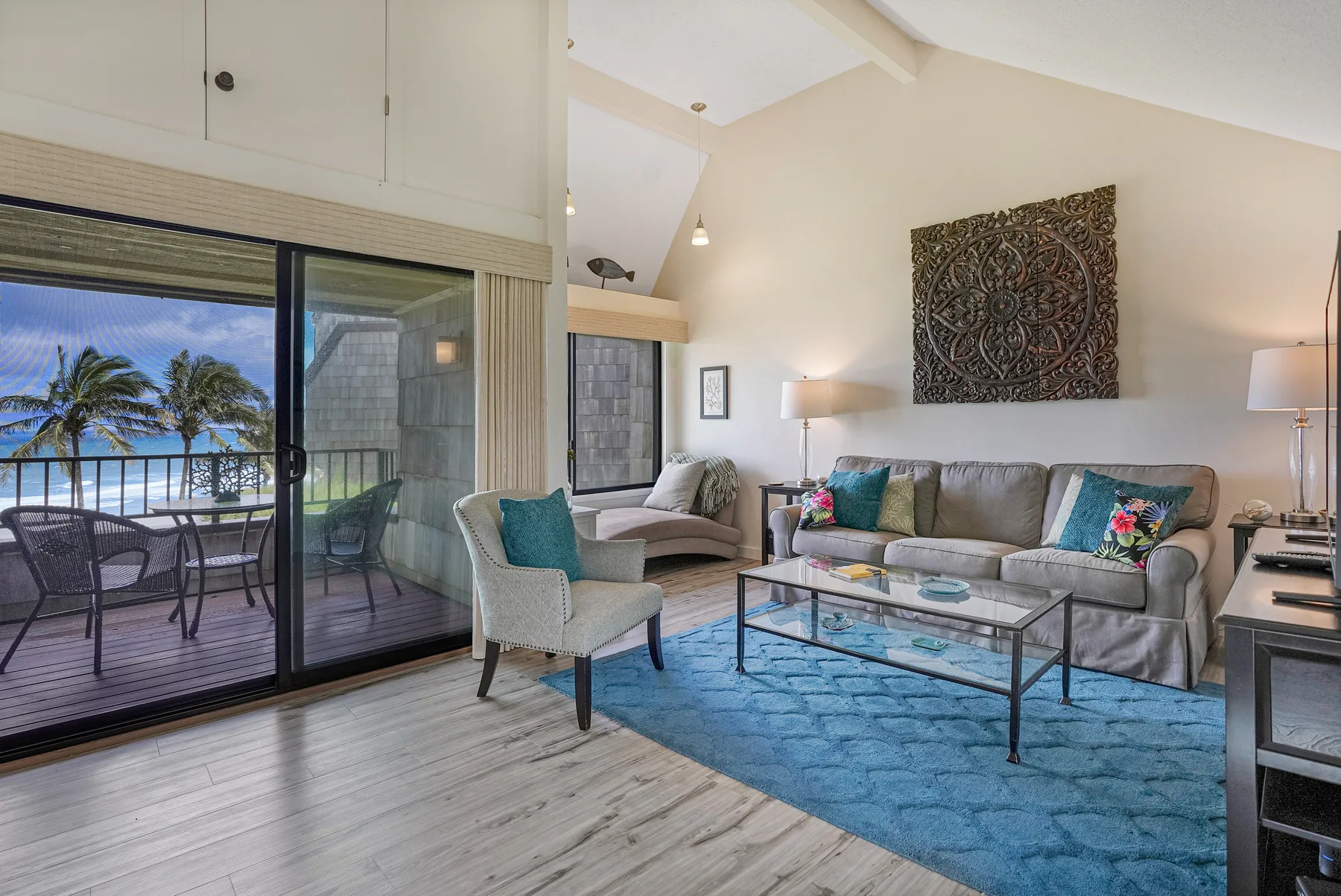 A bright living room with a seating area, glass coffee table, and sliding doors to a balcony.