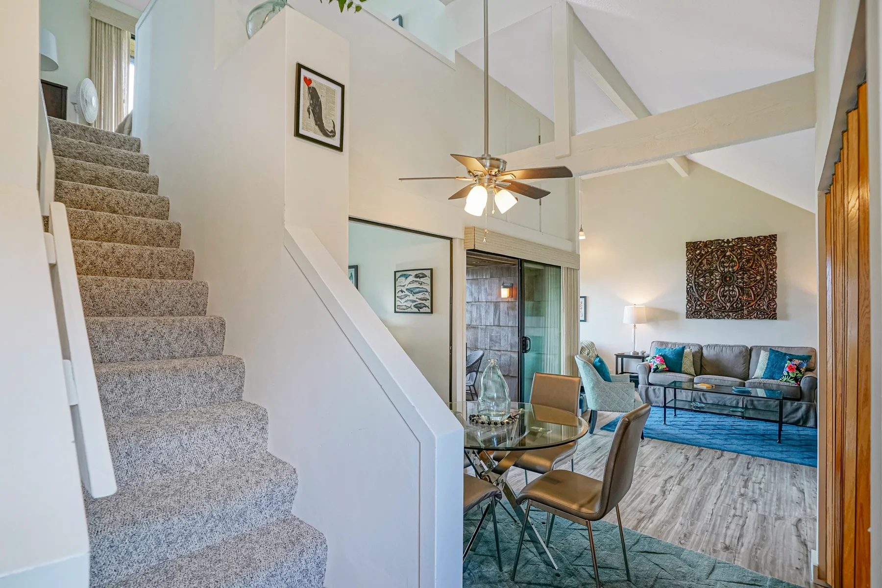 A bright living and dining area with a staircase, seating, and a dining table.