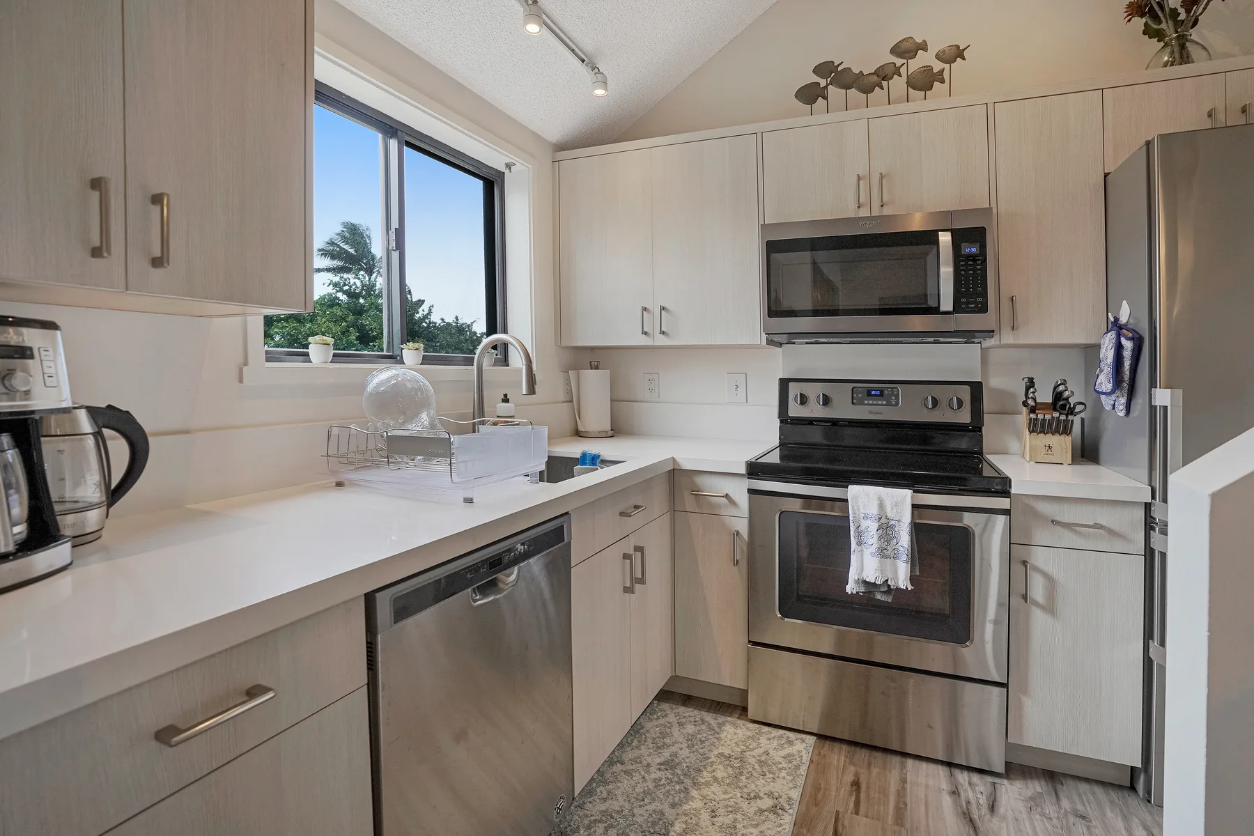 A bright kitchen with light cabinets, stainless steel appliances, and a countertop.
