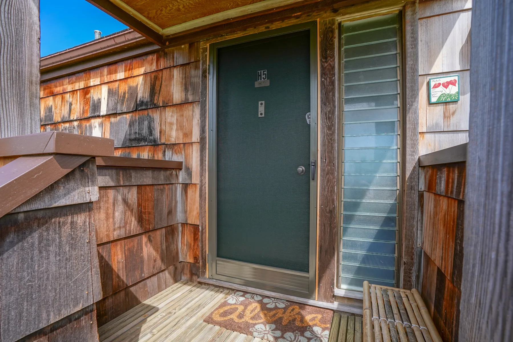 A dark entry door opens onto a small wooden porch.