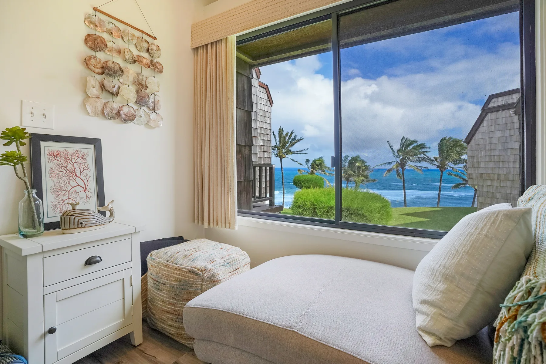 A bright sitting area with cushioned seating beside a large window overlooking the ocean.