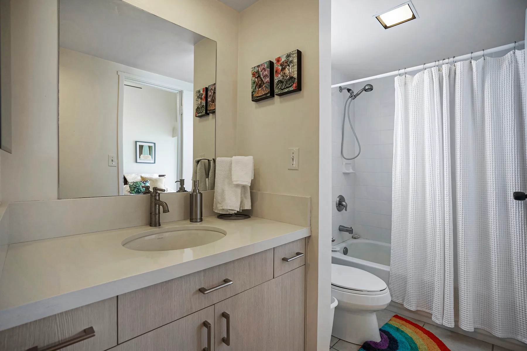 A bathroom vanity and sink sit beside a bathtub and shower with a curtain.