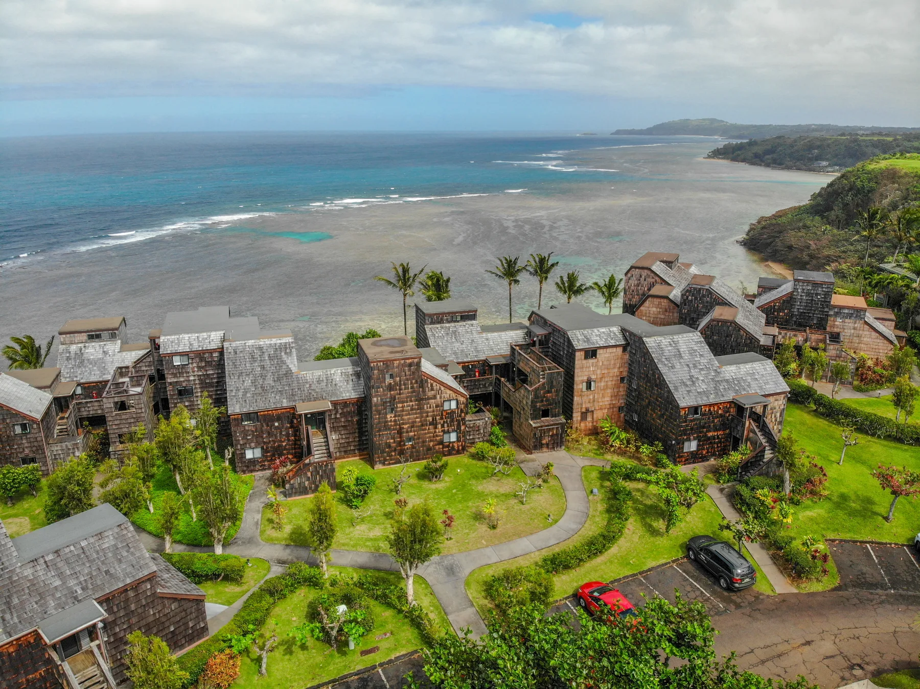 Aerial view of stone buildings beside a coastal beach and turquoise water.