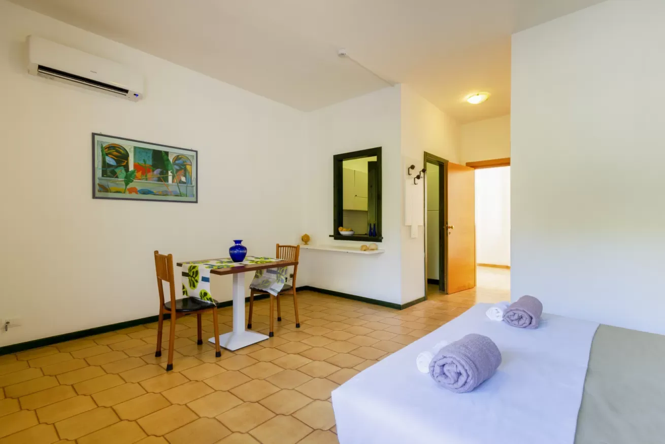 Una habitación luminosa con una mesa pequeña y una cama en primer plano.
