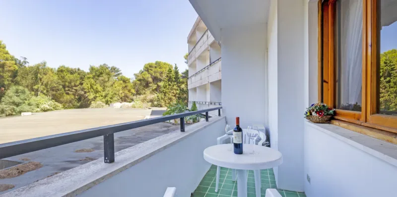 Un balcón con una mesa redonda pequeña y vistas a los árboles.