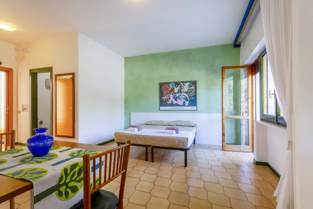 Un dormitorio con una cama junto a una pared verde y una mesa en primer plano.