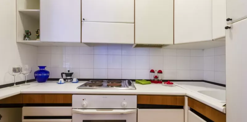 Una cocina compacta con gabinetes blancos y una placa de cocción sobre la encimera.