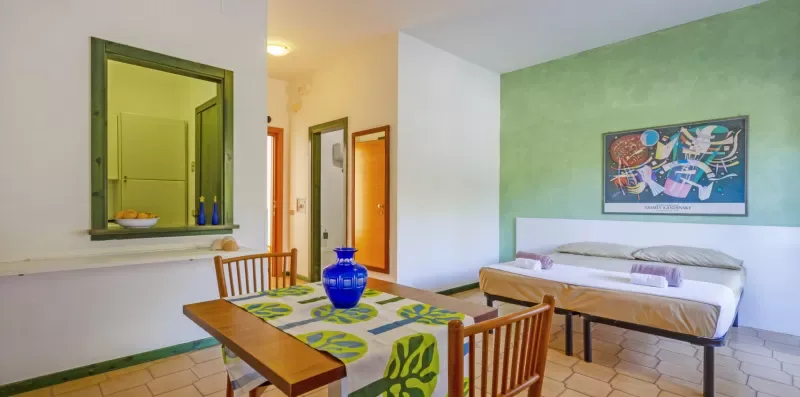 Un dormitorio con una cama, una mesa de comedor y una pared verde.