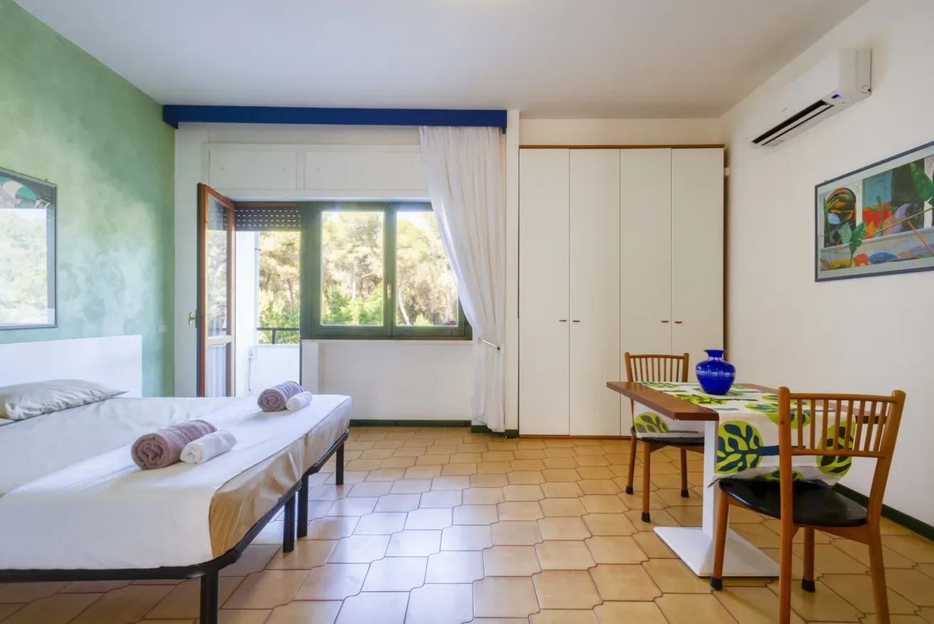 Un dormitorio con una cama junto a una pequeña mesa de comedor con sillas.