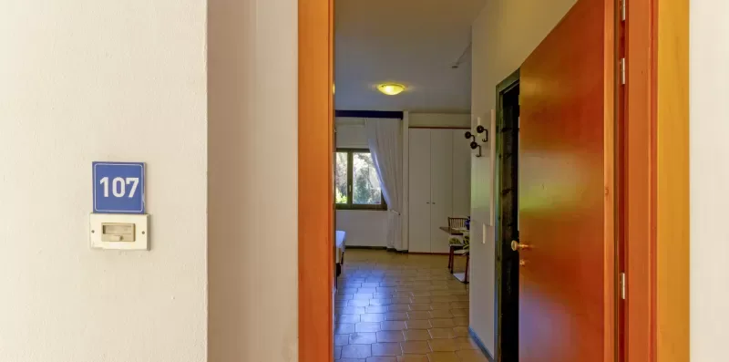 Una entrada de pasillo da a una habitación con suelo de baldosas y una ventana al fondo.