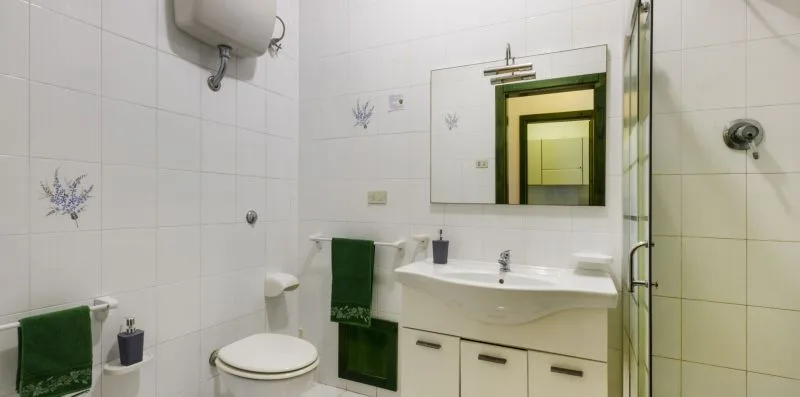 Un baño alicatado con lavabo, espejo y toallas.