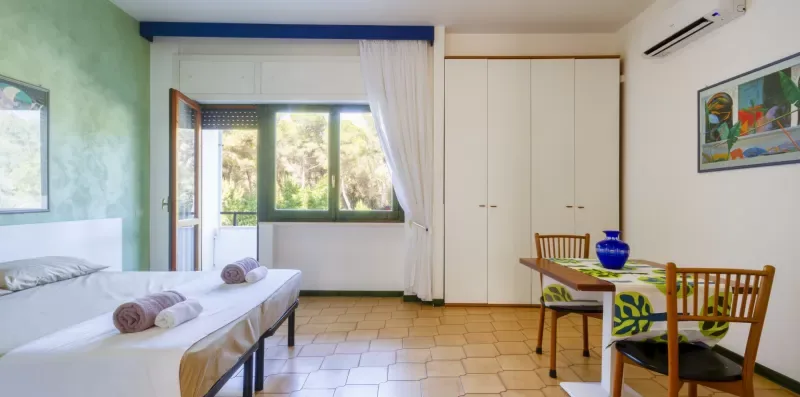 Un dormitorio luminoso con dos camas, un armario y una mesa de comedor.