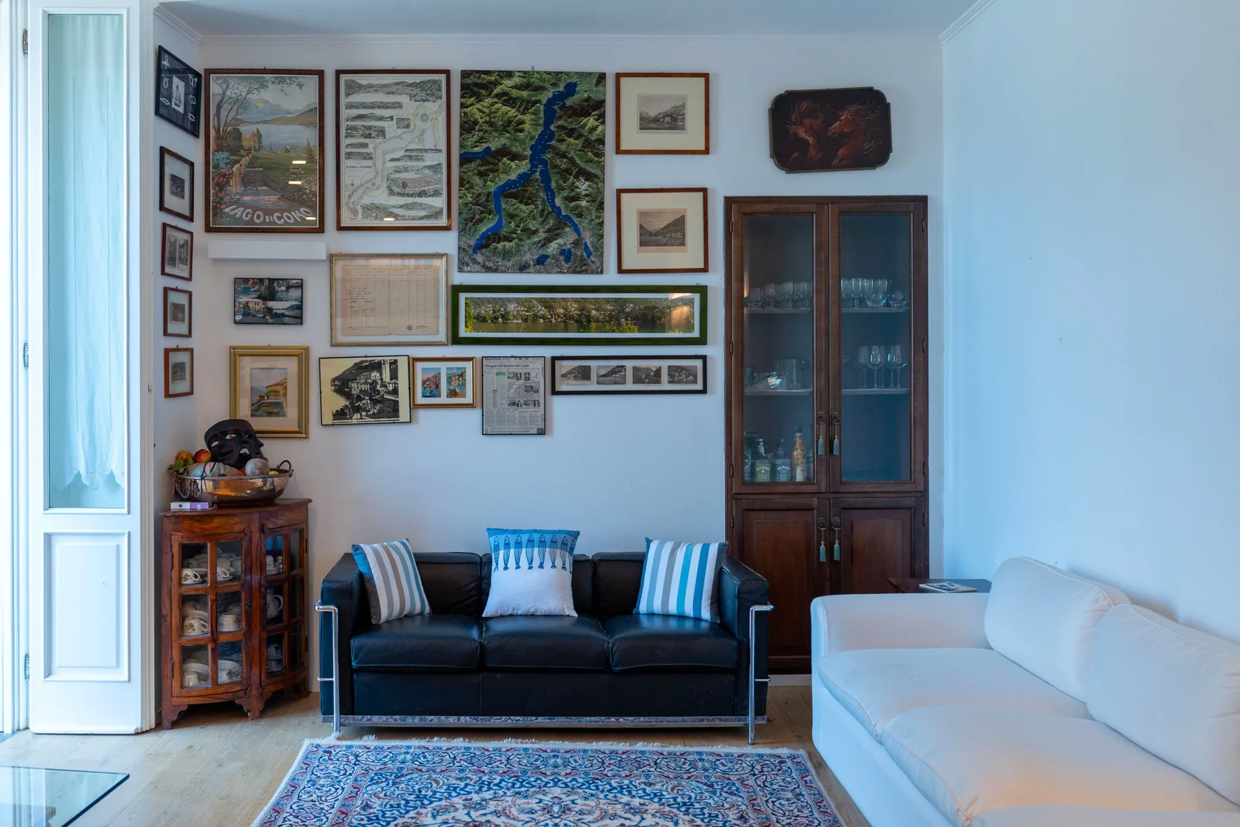 A living room with dark seating, a white sofa, and framed pictures on the wall.