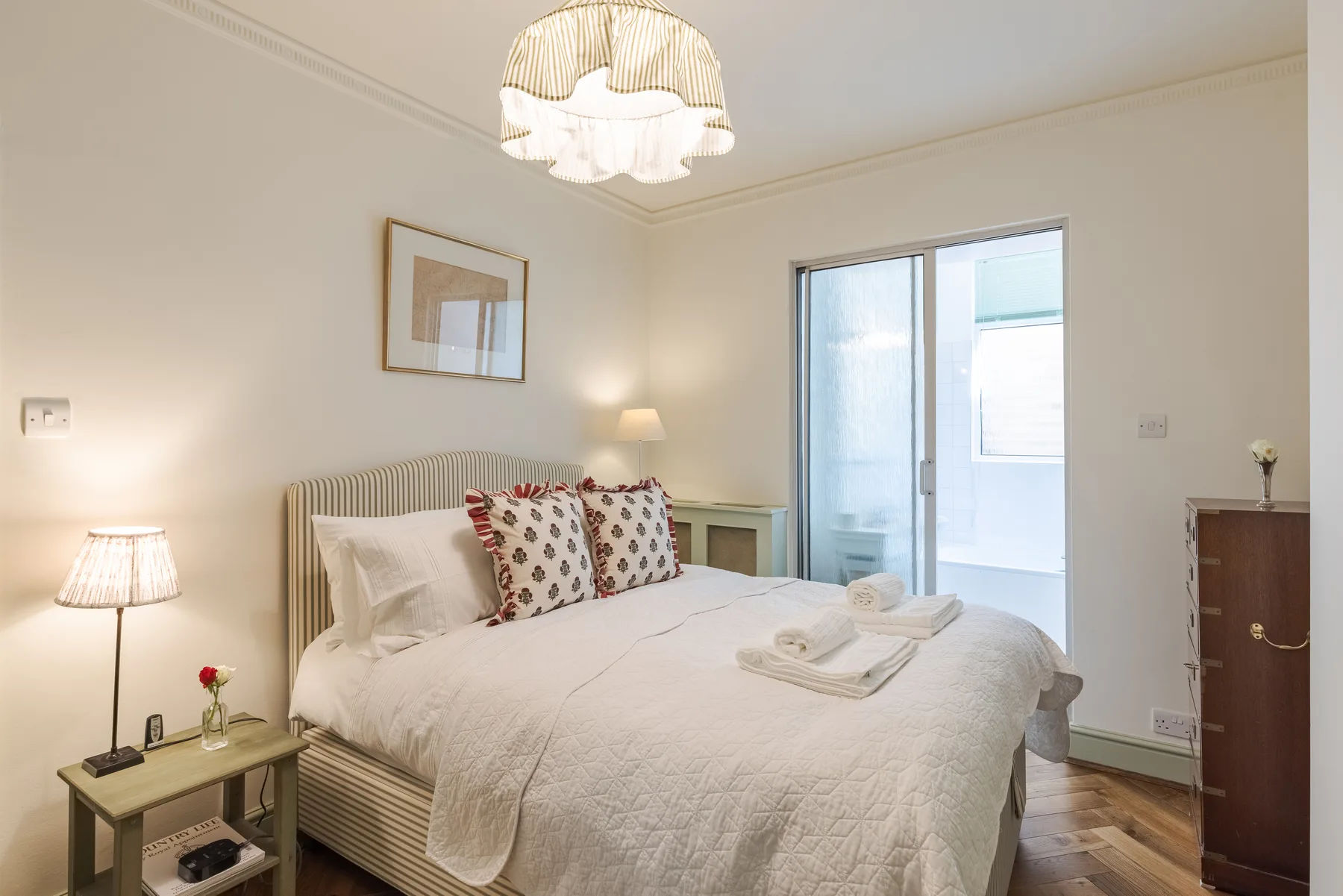 A bright bedroom with a neatly made bed and a glass door opening onto a balcony.