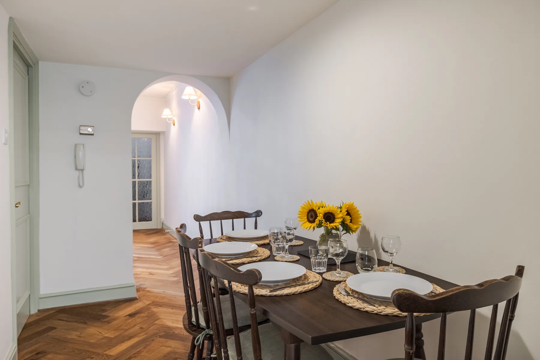 A dining area with a long table set with plates and a vase of sunflowers.