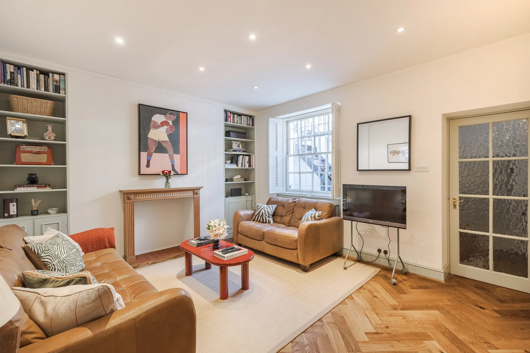 A bright living room with seating around a coffee table and a television.