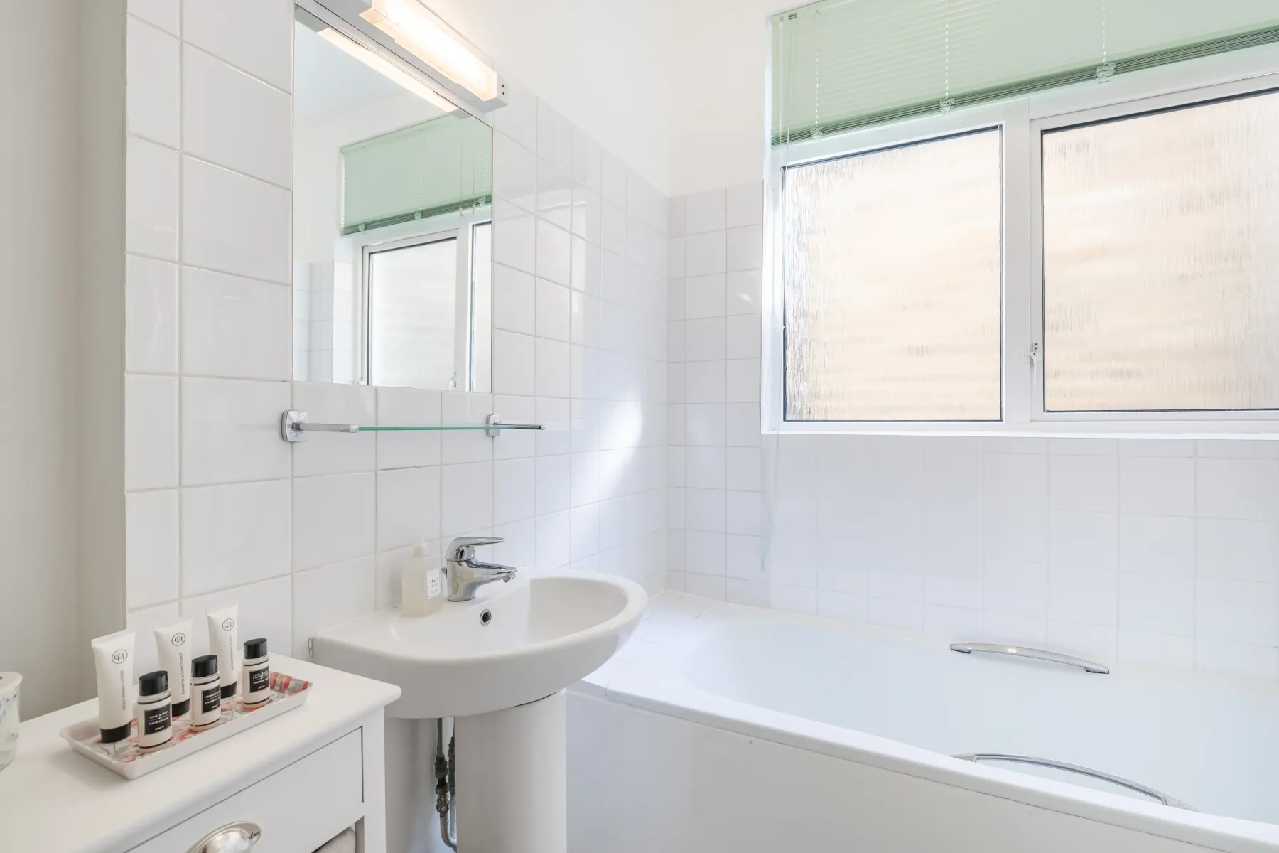 A tiled bathroom with a bathtub, sink, and window.