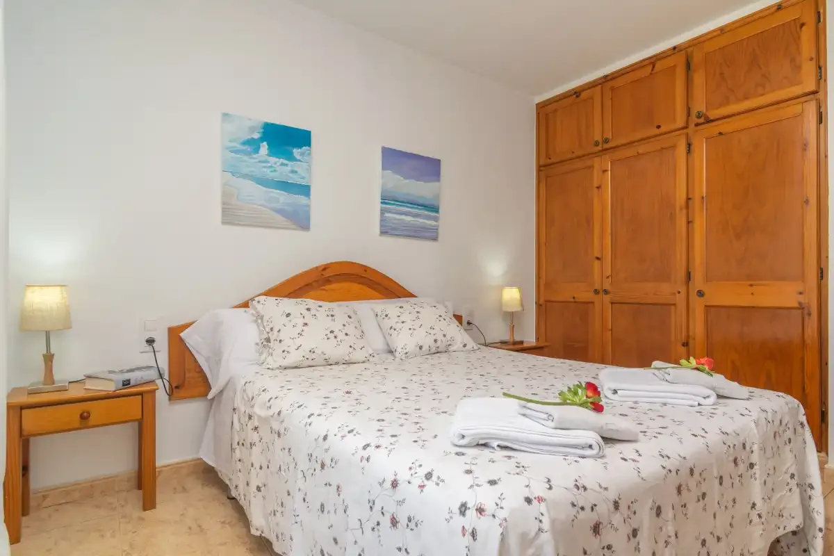 A bedroom with a double bed, bedside tables, and a wooden wardrobe.